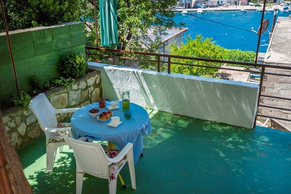 A balcony with a table set for two, overlooking a marina with boats. - Apartments Senka (Sibenik)