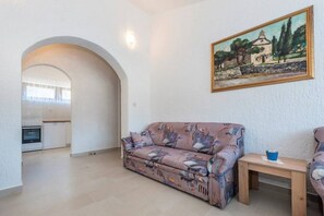 A living room with a sofa, a painting, and a small table. - Apartments Senka (Sibenik)