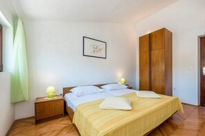 A bedroom with a bed, nightstands, a wooden wardrobe, and a framed picture on the wall. - Apartments Senka (Sibenik)