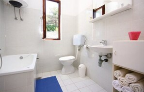 A bathroom with a toilet, sink, and bathtub. - Apartments Senka (Sibenik)