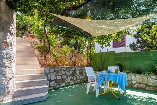 A stone staircase leading to a covered outdoor area with a table and chairs. - Apartments Senka (Sibenik)