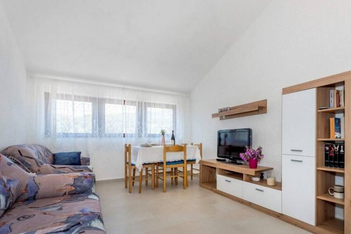 A modern living room with a sofa, a dining table, and a TV.