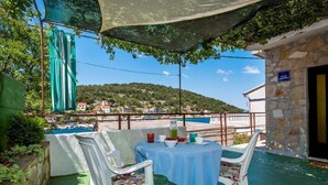 Eine Terrasse mit Tisch und Stühlen, im Hintergrund ein Schwimmbecken und eine Steinmauer.