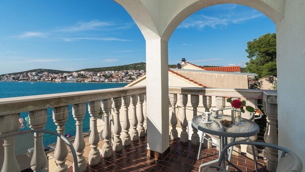 Un balcon avec vue sur la mer et sur une ville située au loin.