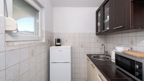 Une cuisine compacte équipée d’un réfrigérateur, d’un four à micro-ondes, d’un évier et d’un plan de travail en bois.