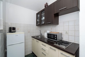 Una cucina compatta con frigorifero, microonde, fornelli e pensili.