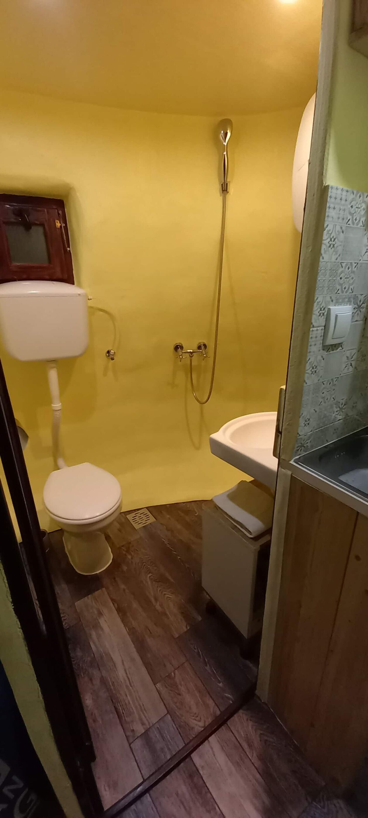 A small bathroom with a toilet, sink, and shower.