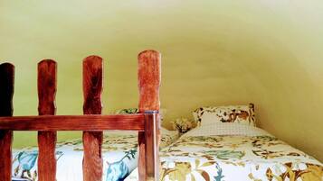 A small, cozy room with a bed featuring a floral bedspread and a wooden headboard.