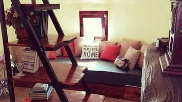 A living room with a staircase, a sofa, and a sign that reads "There is no place like HOME."