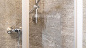 Ducha con cabezal de ducha de mano y grifo empotrado en una pared con azulejos.