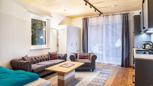 Una sala moderna con un sofá, una mesa de centro y una cocina con un fregadero y armarios.