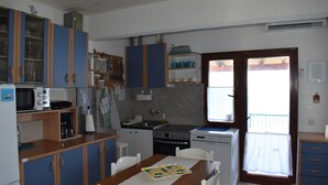 A compact kitchen with a dining area, featuring cabinets, a microwave, a stove, and a sink. - Apartment Marijana (Seget)