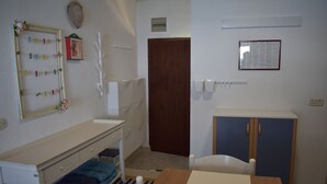 A room with a wooden table, a white chair, a blue cabinet, and a white shelf with folded blankets. - Apartment Marijana (Seget)