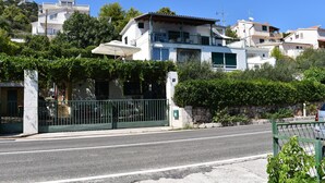 A residential building with a balcony, a stone wall, and a green fence. - Apartment Marijana (Seget)