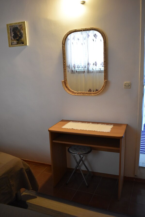 Une petite salle de bain avec un meuble-lavabo en bois, un miroir avec un cadre décoratif, un petit tabouret et un tableau encadré accroché au mur.