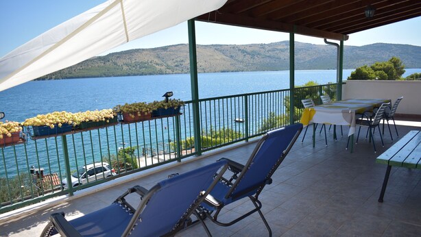 A covered outdoor seating area with a view of a lake and hills. - Apartment Marijana (Seget)
