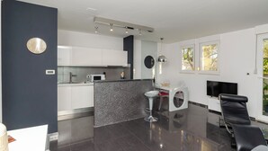 Cocina moderna con armarios blancos, encimera de granito y una barra con un taburete.