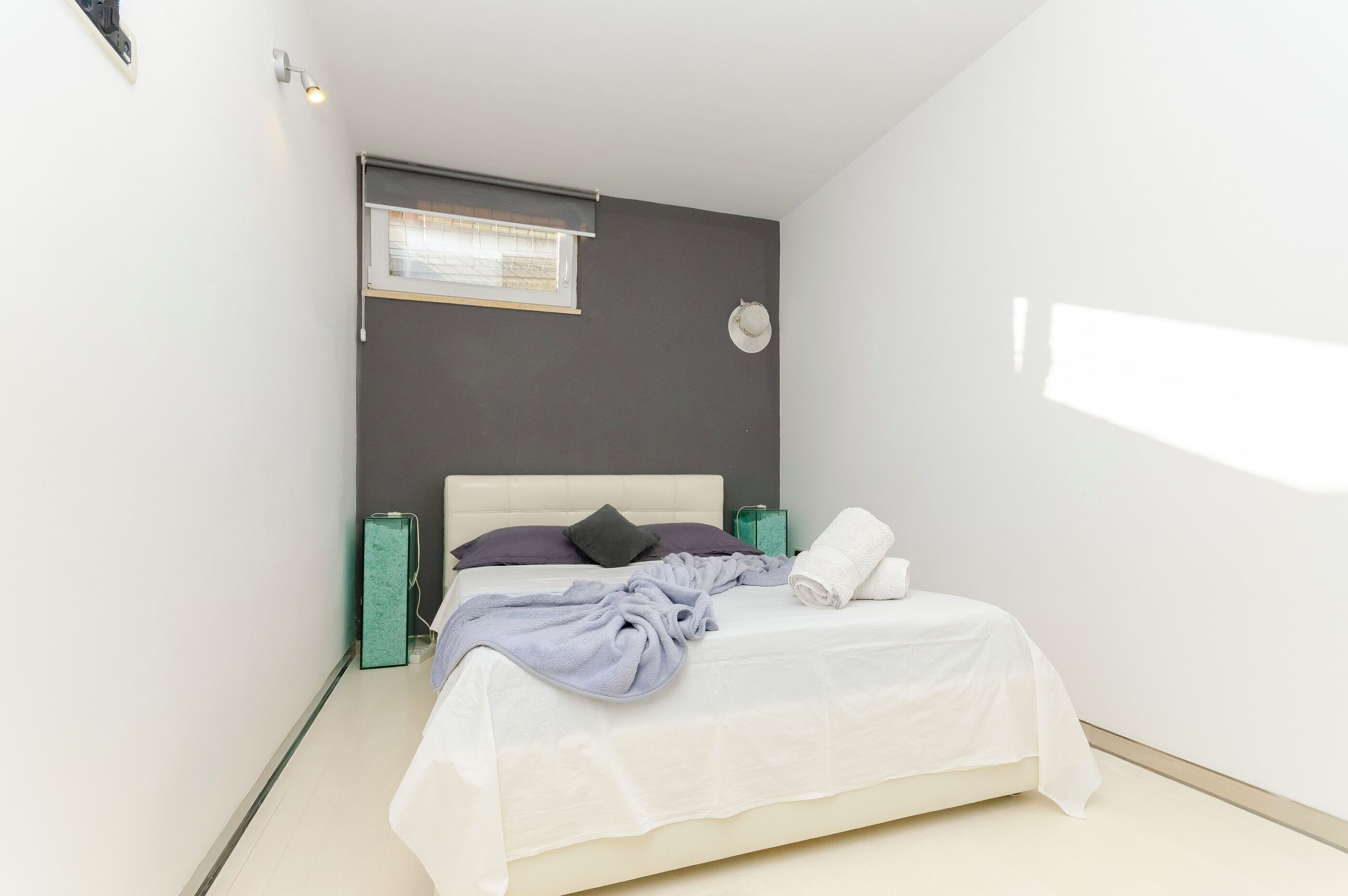 Ein Schlafzimmer mit Bett, Fenster, Wanduhr und Nachttisch.