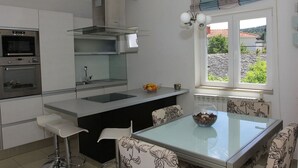 Eine moderne Küche mit einer zentralen Kochinsel, eingebauten Backöfen und einem großen Fenster mit Blick.