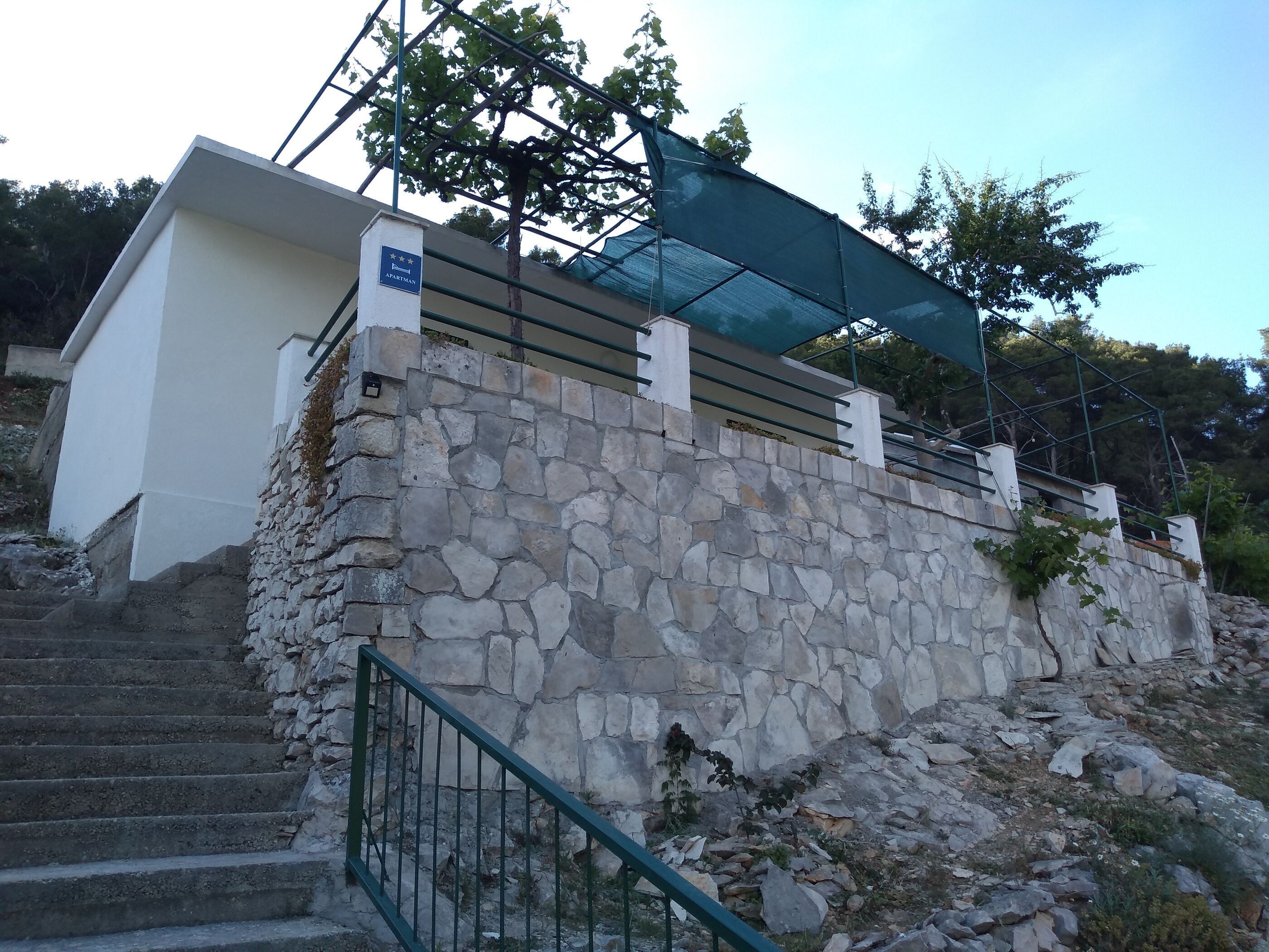 A stone staircase leading to a building with a sign reading "APARTMAN".