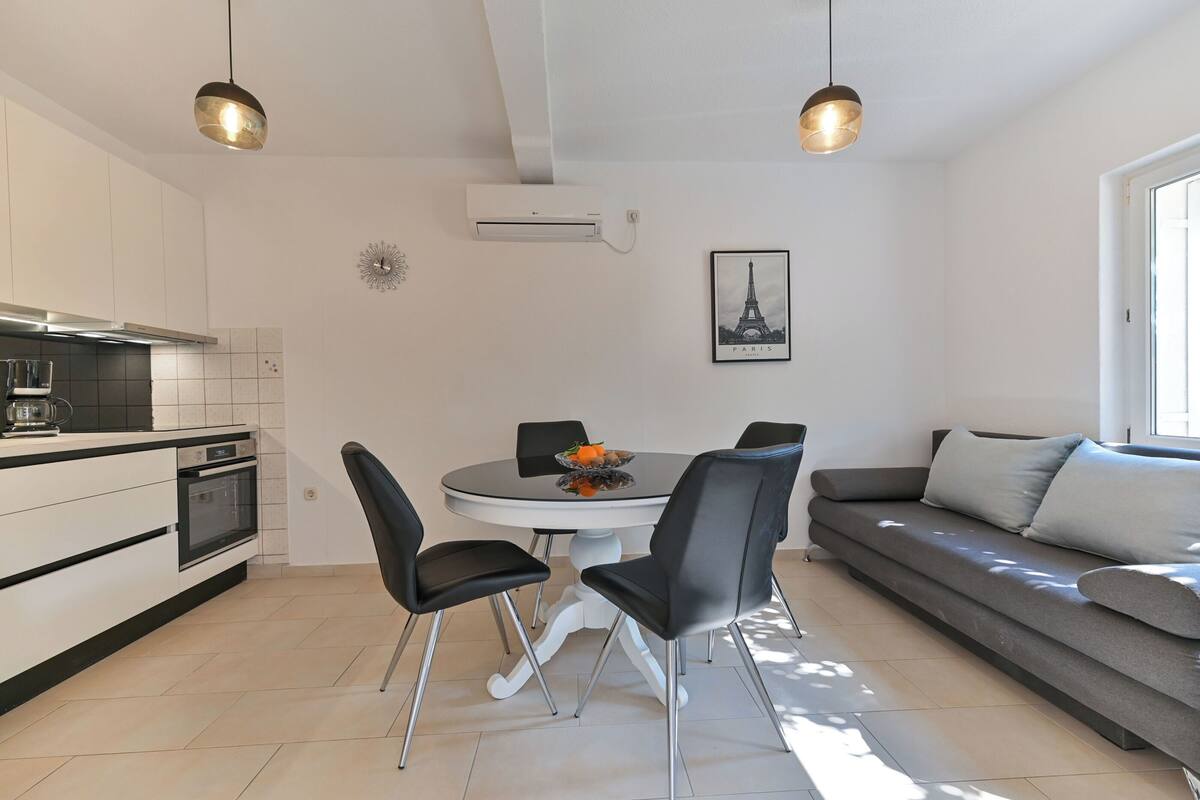 A modern kitchen with a dining area, a sofa, and a pendant light.