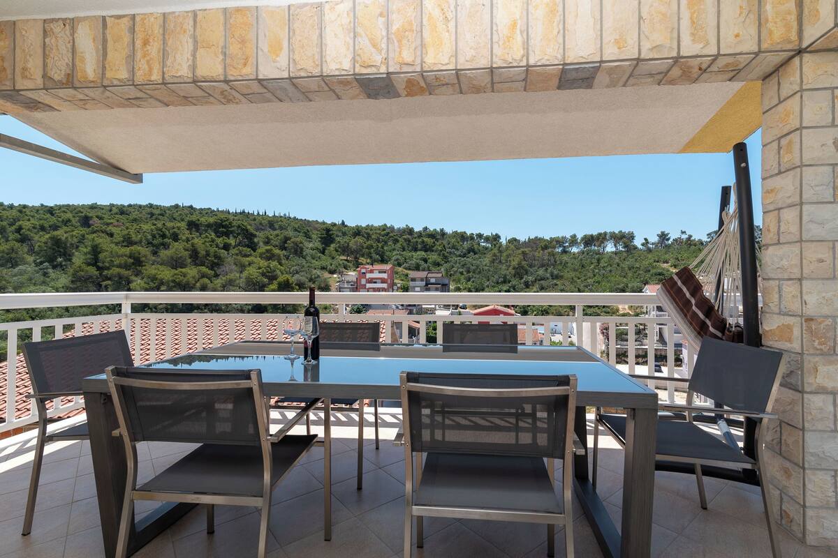 A terrace with a table and chairs, overlooking a mountainous landscape.