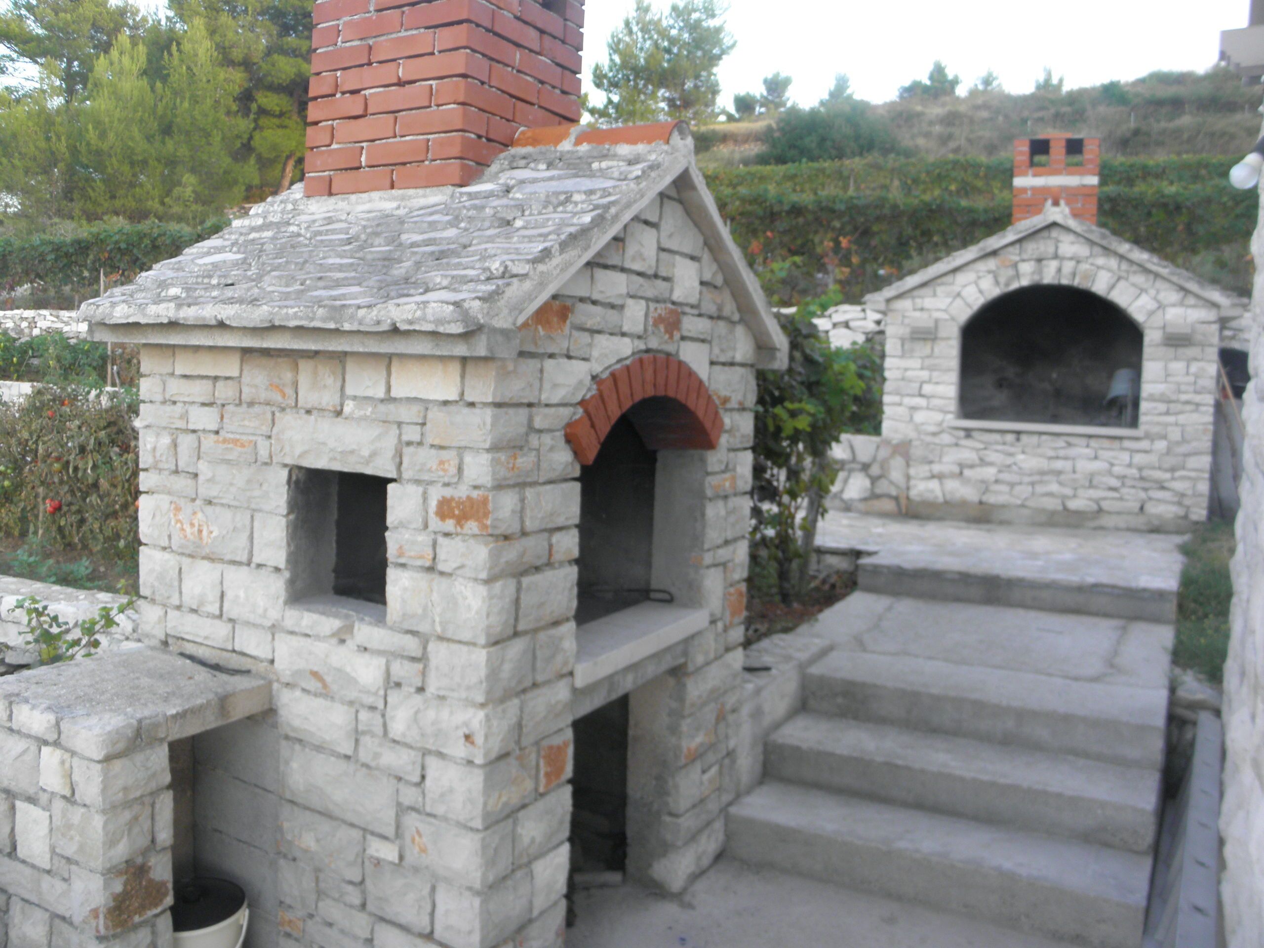 Ein Steinhaus mit Ziegelkamin, kleinem Rundbogenportal und einem Steinkochherd.