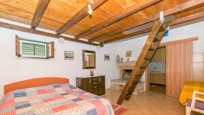 Una camera da letto con soffitto in legno, un letto con copriletto, un comò, uno specchio e una scala che conduce a un'altra stanza.