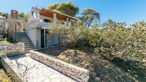 Una casa in pietra con un portico in legno, una scala che conduce all'ingresso e vista sul paesaggio circostante.