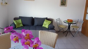 A living room with a sofa, chairs, a small table, and a wall-mounted air conditioner. - Apartments Adriatic (Rogoznica)