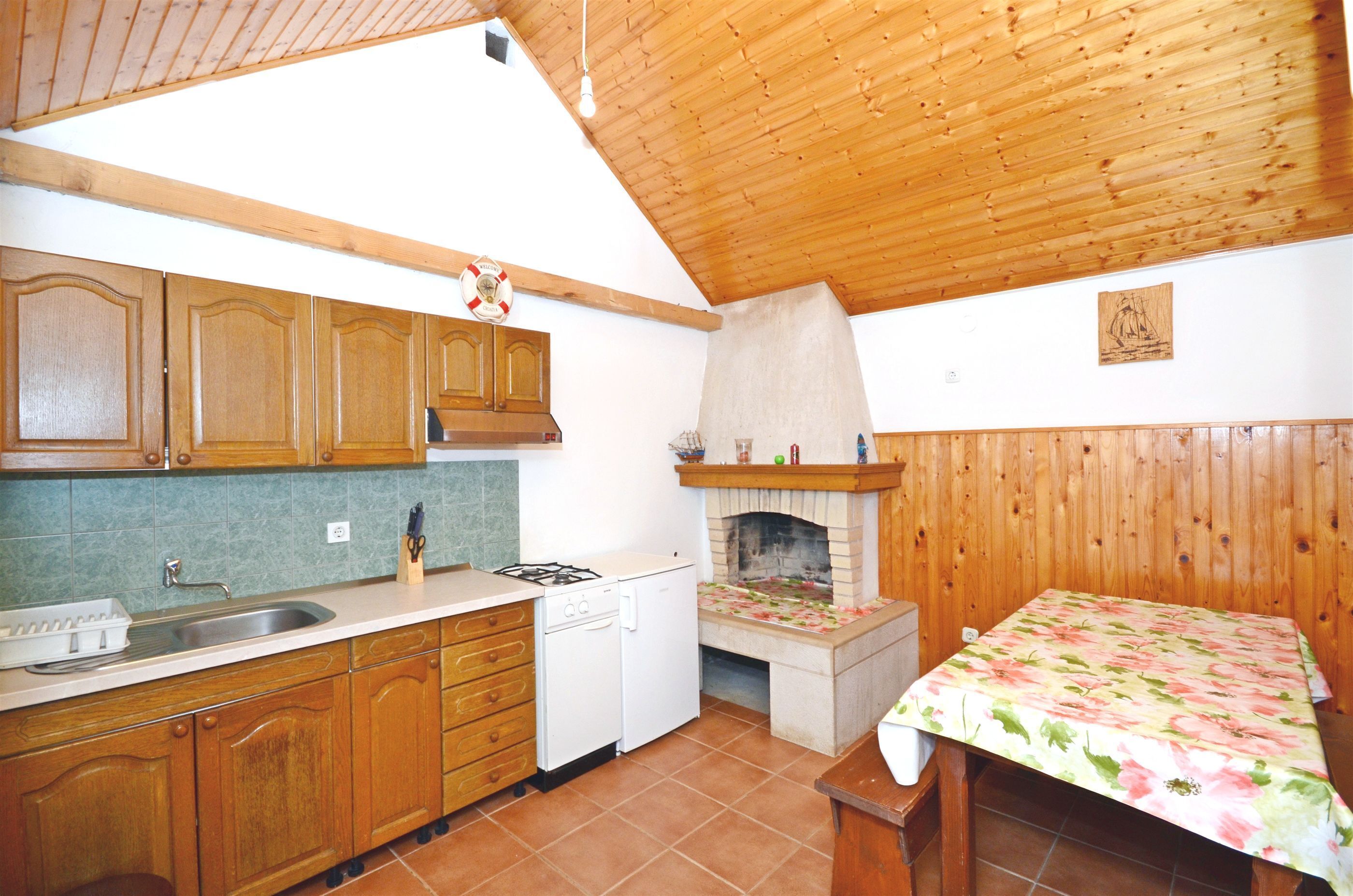 A kitchen with wooden cabinets, a sink, a stove, and a fireplace.