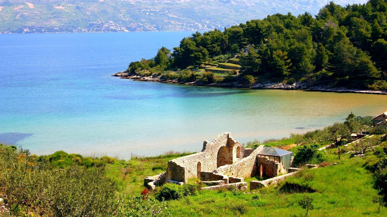 A coastal landscape with ruins and a clear view of the sea.
