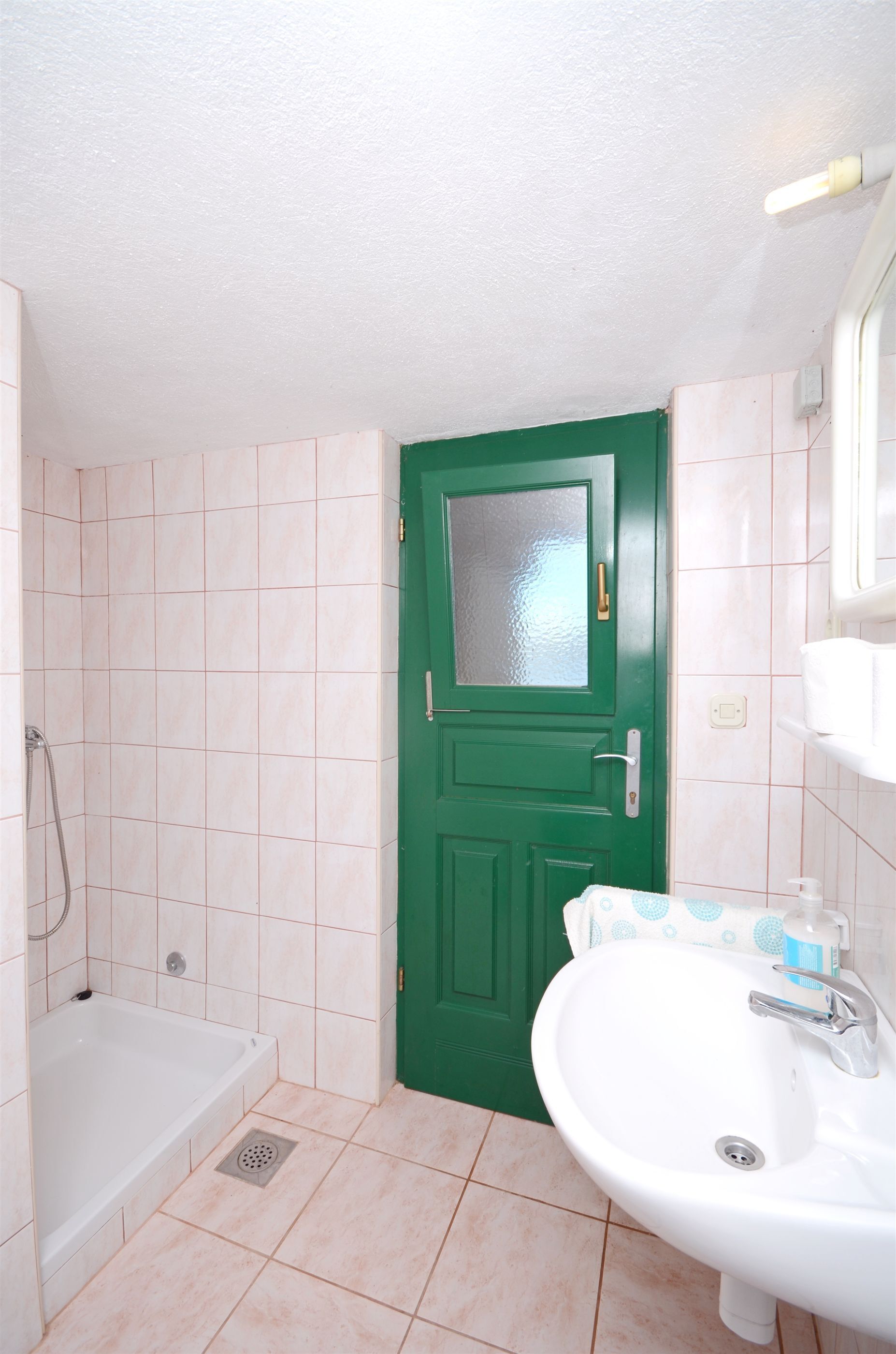 A bathroom with a green door, a white sink, and a bathtub.