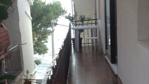 A balcony with a tiled floor, a table, and chairs. - Apartments Soline (Podgora)
