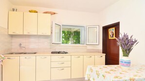 Eine Küche mit Fenster, Spüle und Tisch mit Blumenmuster auf der Tischdecke.