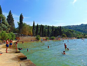 A public swimming area with people swimming and sunbathing, surrounded by trees and a stone wall. - House Sv. Lovre (Postira)