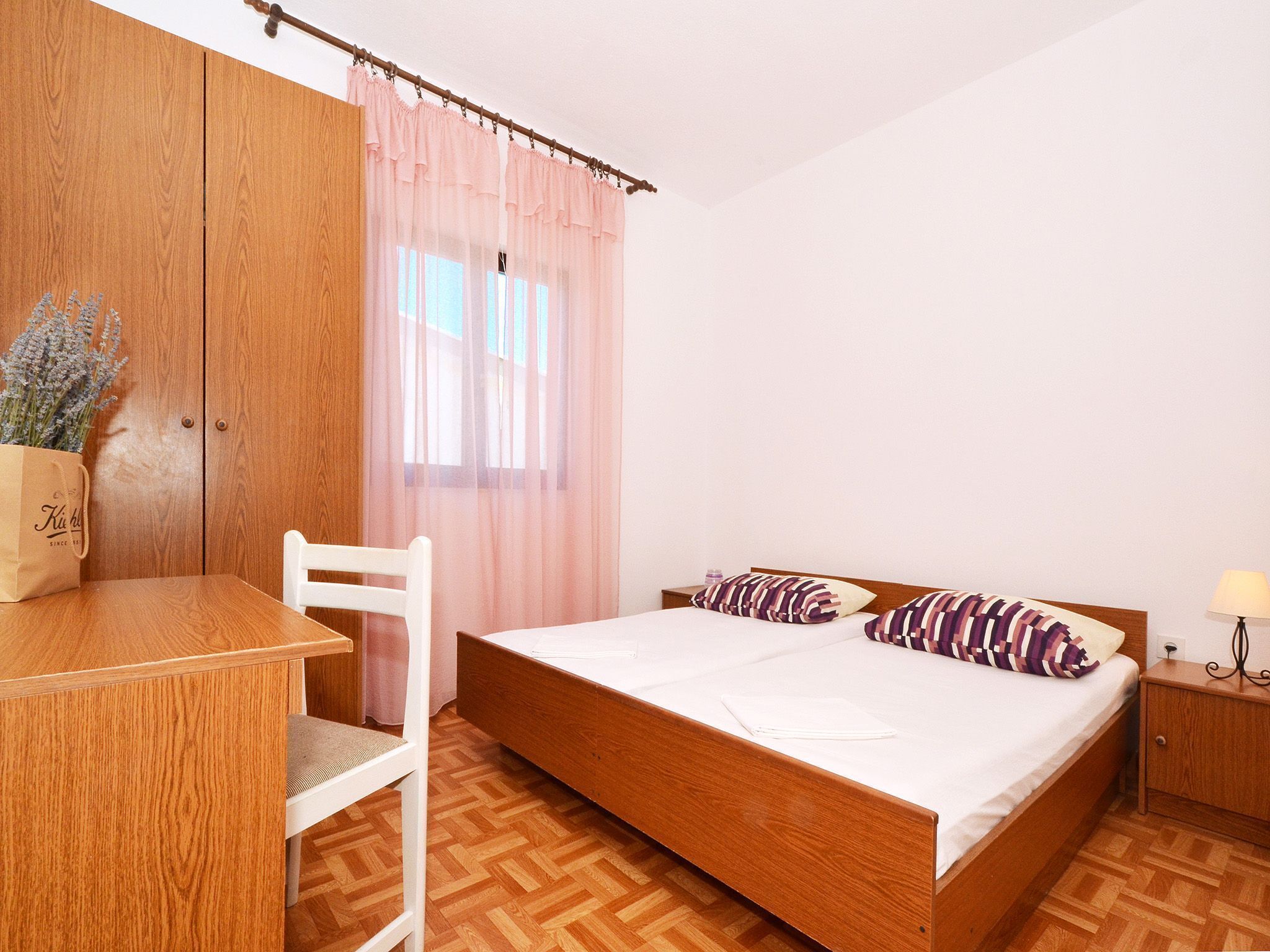 A bedroom with a wooden bed, a desk, and a chair.