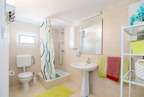 A bathroom with a toilet, sink, bathtub, and shower. - House Marija (Postira)