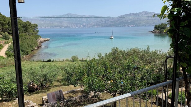 A coastal landscape with a clear view of the sea, a sailboat, and distant mountains. - House Ivica (Postira)