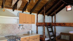 A rustic kitchen with wooden beams, a stove, and a ladder. - House Ivica (Postira)