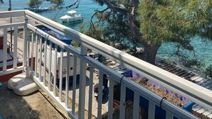 A balcony with a view of the sea, a tree, and a boat.