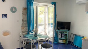 A compact living space with a dining area, a television, and a kitchenette.