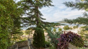 A stone staircase leading to a terrace overlooking a body of water, with lush greenery and a view of boats. - Apartment Sofi (Crikvenica)