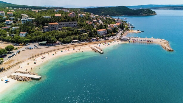 An aerial view of a coastal town with a beach, clear blue waters, and buildings with red roofs. - Apartment Sofi (Crikvenica)