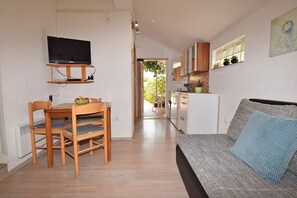 A compact living space with a dining area, a sofa, a kitchen, and a TV mounted on the wall. - Apartments Petra (Fazana)