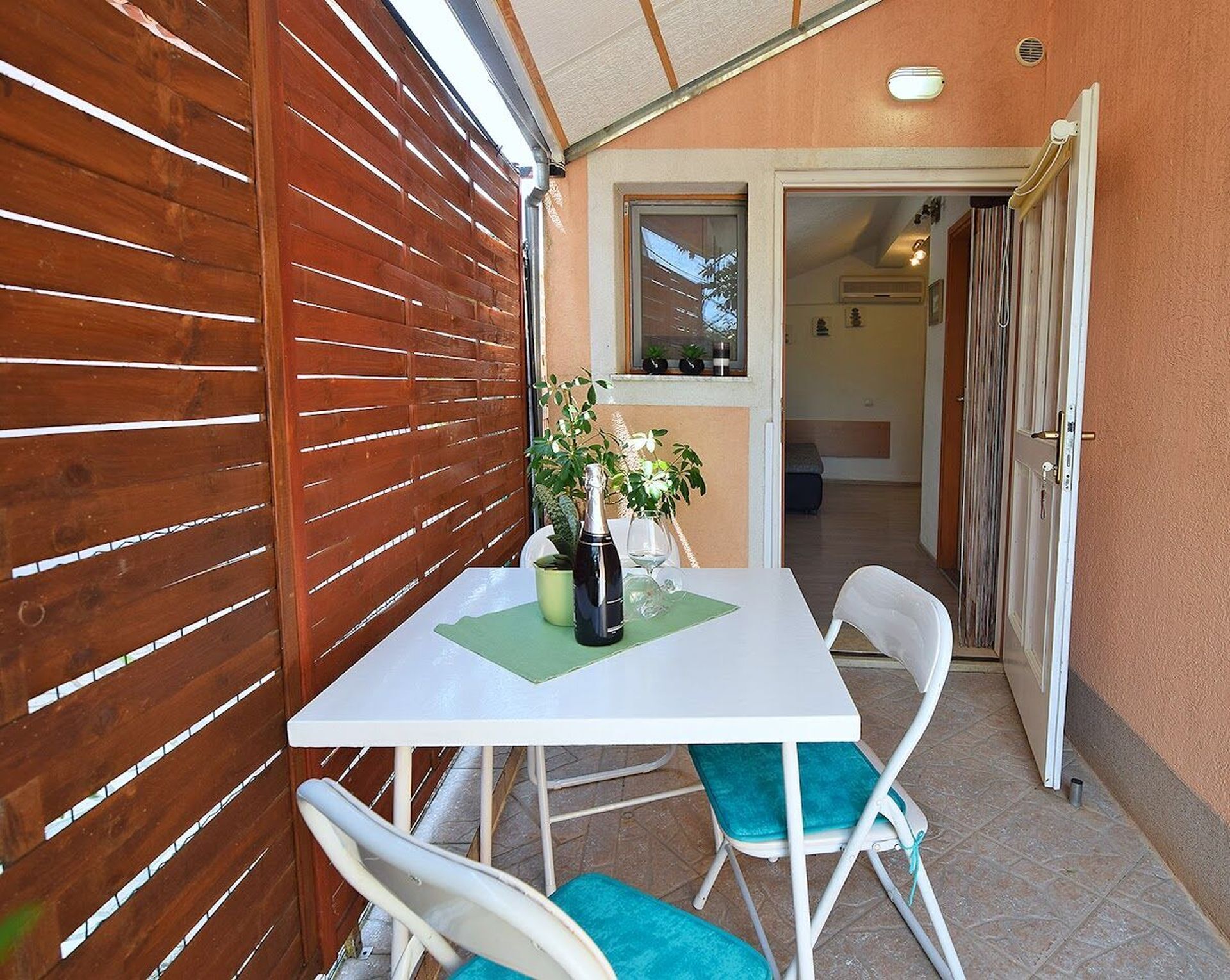 A patio with a table, chairs, and a bottle of champagne.