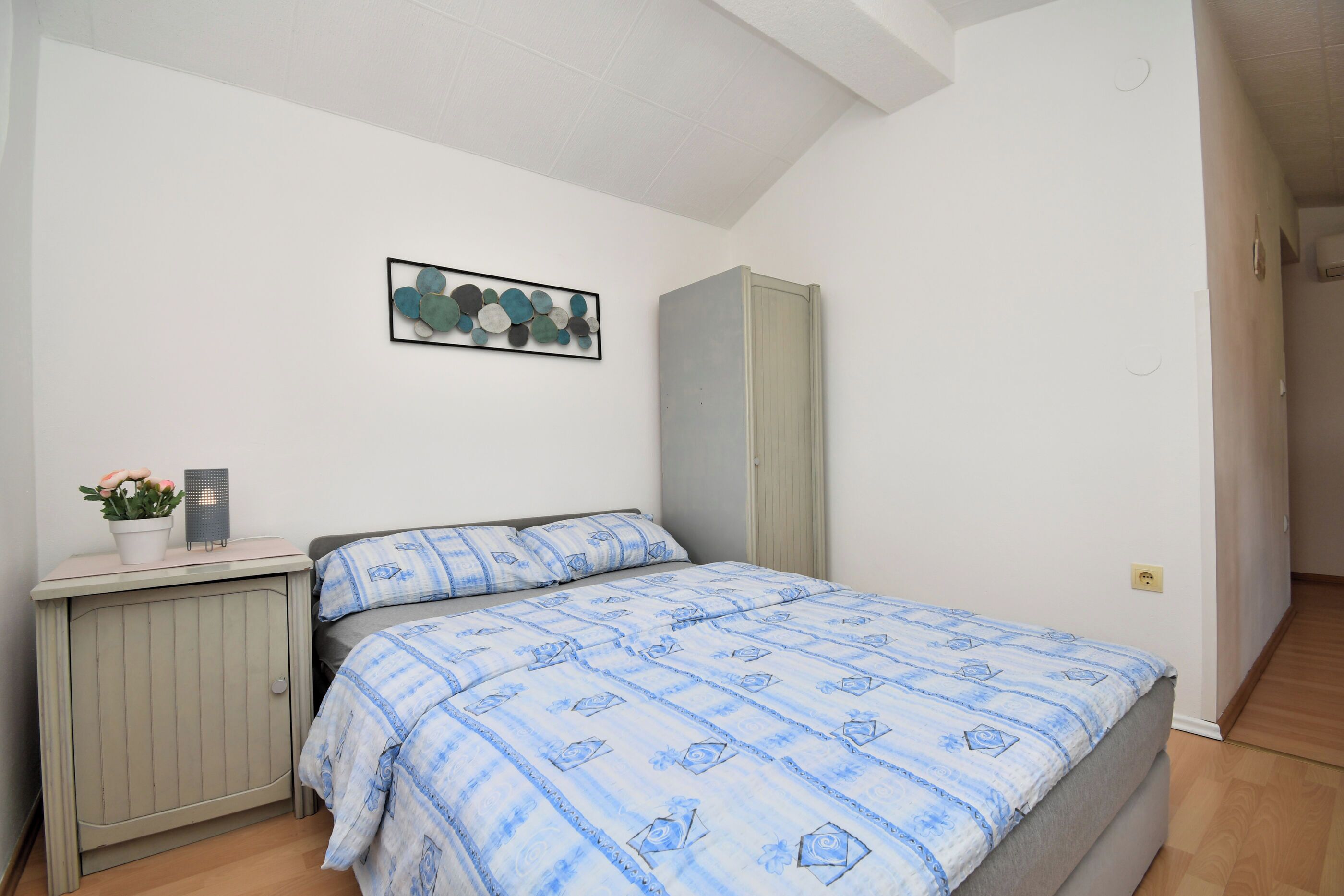 Una camera da letto con un letto, un comodino, una cassettiera e un'opera d'arte appesa al muro.