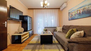 Ein Wohnzimmer mit einer Couch, einem Couchtisch, einem Flachbildfernseher und einem Bild an der Wand.