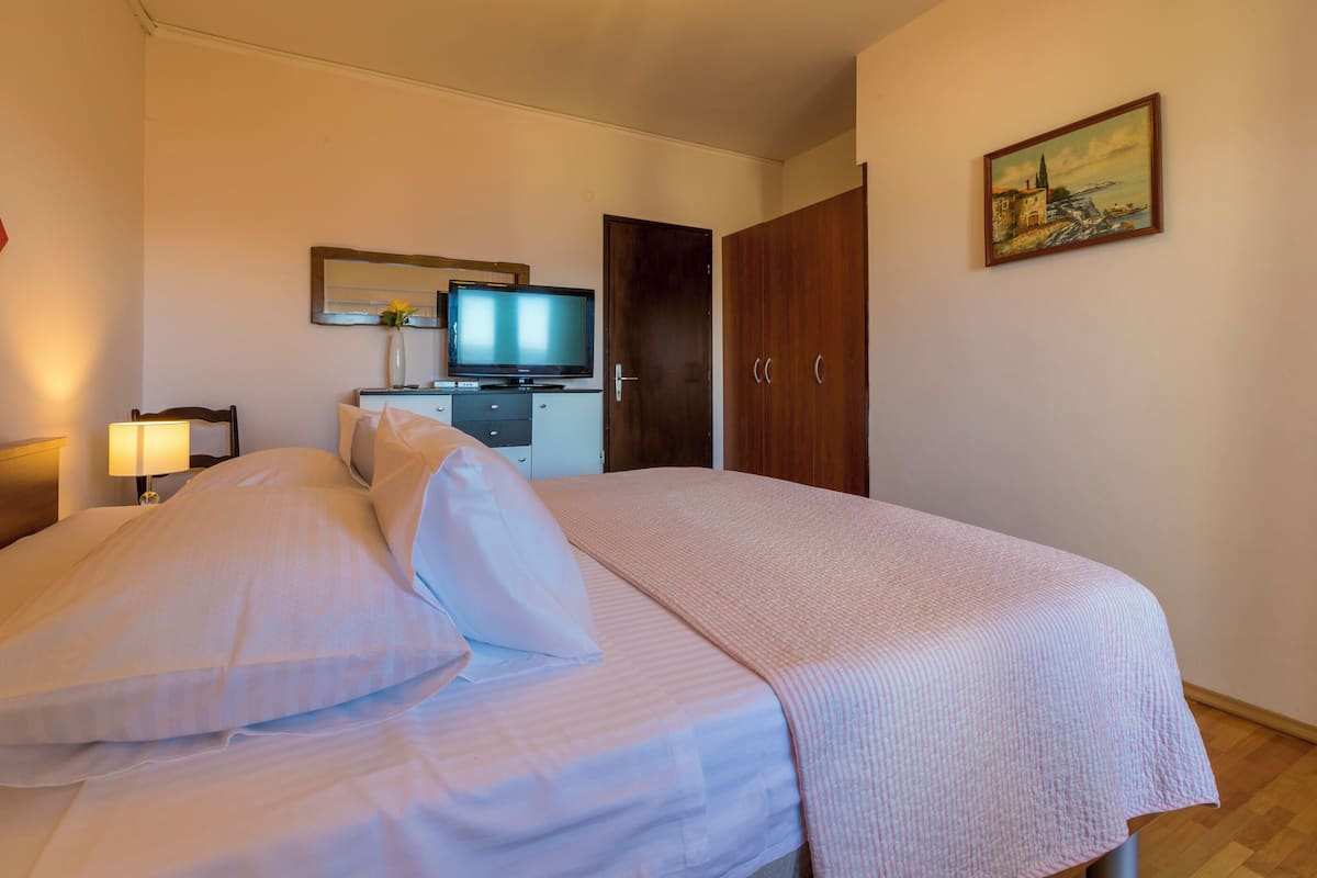 Une chambre d’hôtel comprenant un lit, une télévision, un bureau avec un ordinateur et une armoire.