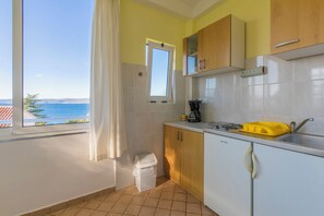 A kitchen with a view of the sea, a window with a curtain, and a sink. - Apartments and Rooms Dotli (Crikvenica)